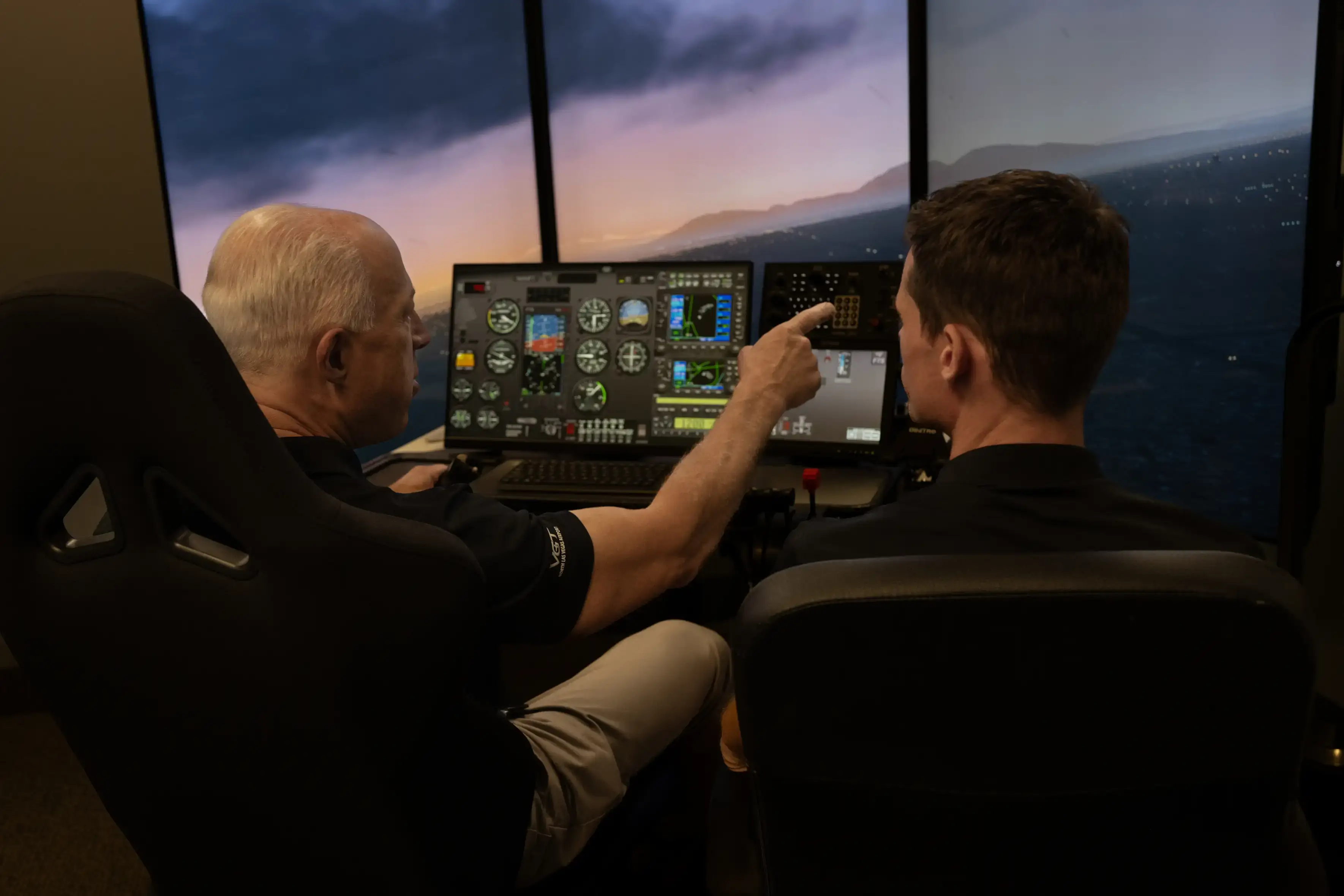 Backview of two men using a flight simulator