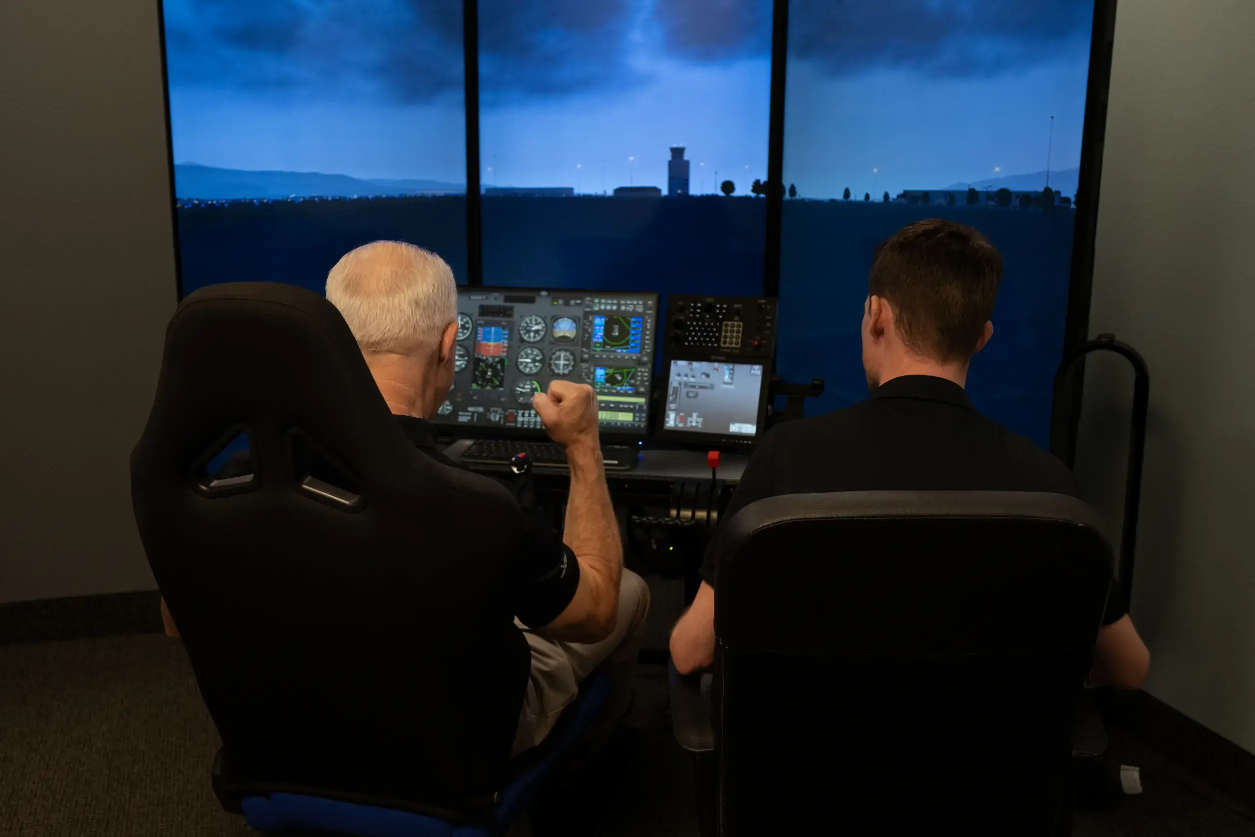 Backview of two people using a flight simulator